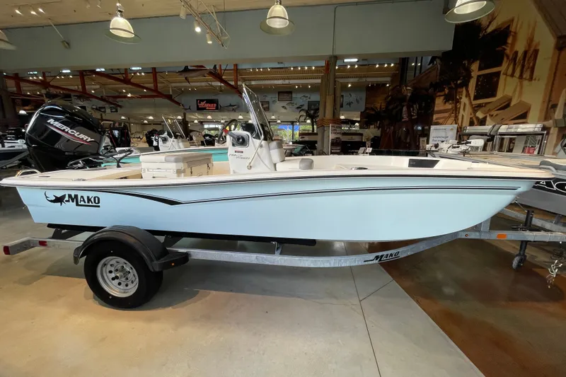 Slide: The Image of 2026 Mako Pro Skiff 15 CC boat on trailer in showroom setting. - 2