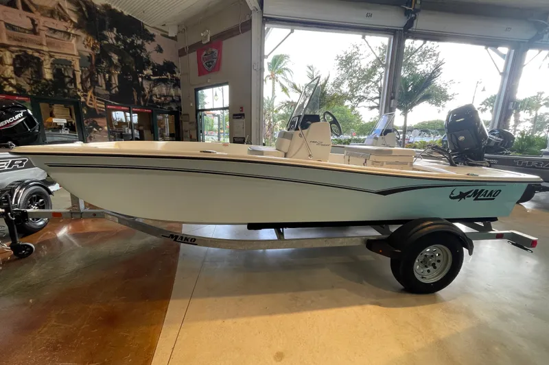 Slide: The Image of 2026 Mako Pro Skiff 15 CC boat on trailer in showroom setting. - 1