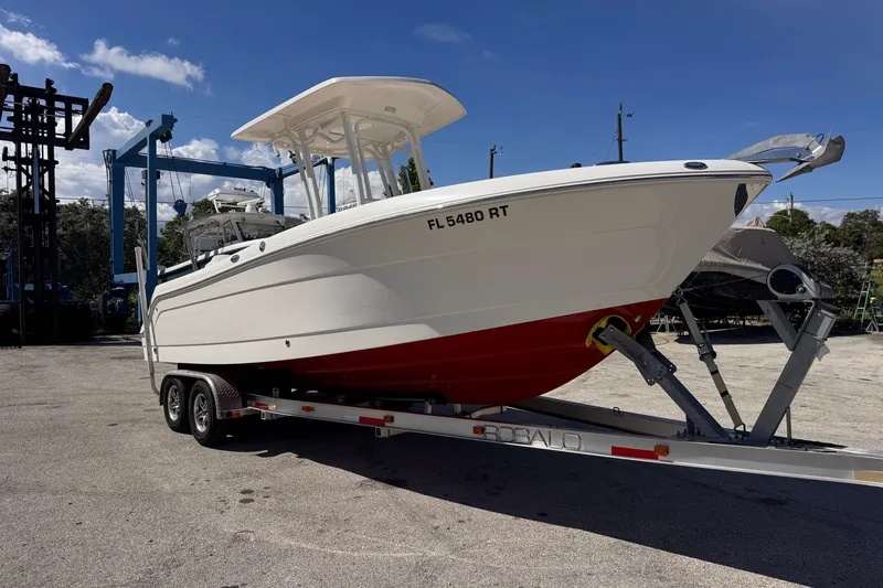 The Image of 2017 Robalo R242 Center Console boat on trailer, parked outdoors under blue sky. - 0