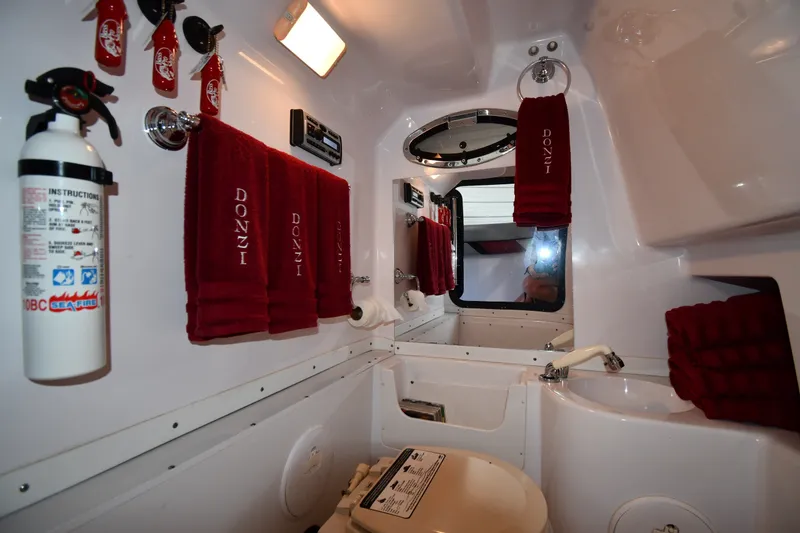 Slide: The Image of Interior of 2009 Donzi 38 ZFX Open boat bathroom with red towels and safety equipment. - 43
