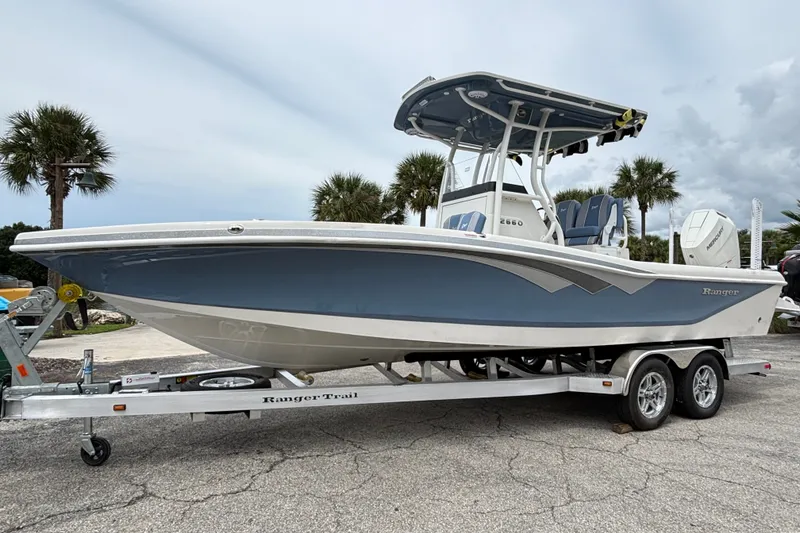 The Image of 2027 Ranger 2660 Bay boat on trailer, parked outdoors with palm trees in background. - 0