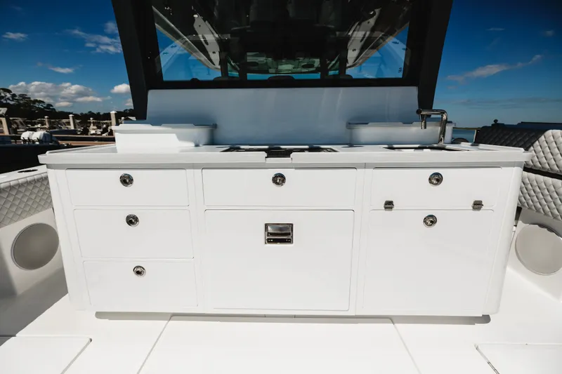 Slide: The Image of Luxury outdoor kitchen on 2026 HCB 48 Campeón boat, featuring sleek white cabinetry. - 57