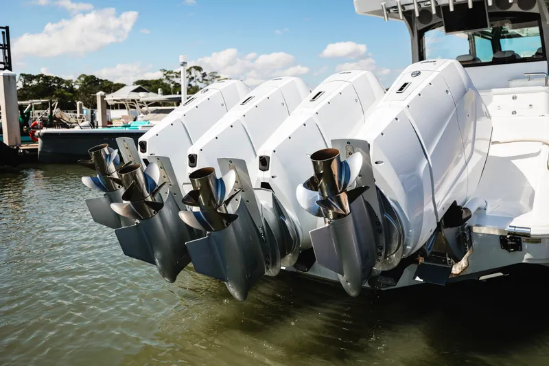 Slide: The Image of Four powerful outboard motors on a 2026 HCB 48 Campeón boat, docked in calm waters. - 46