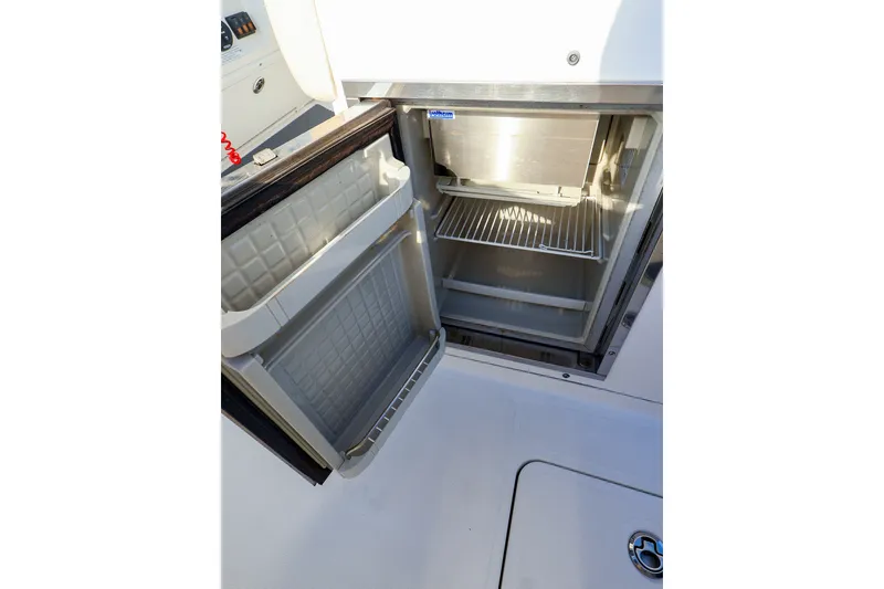 Slide: The Image of Open refrigerator on 2015 Southport 33 FE boat, showcasing interior shelves and storage space. - 17