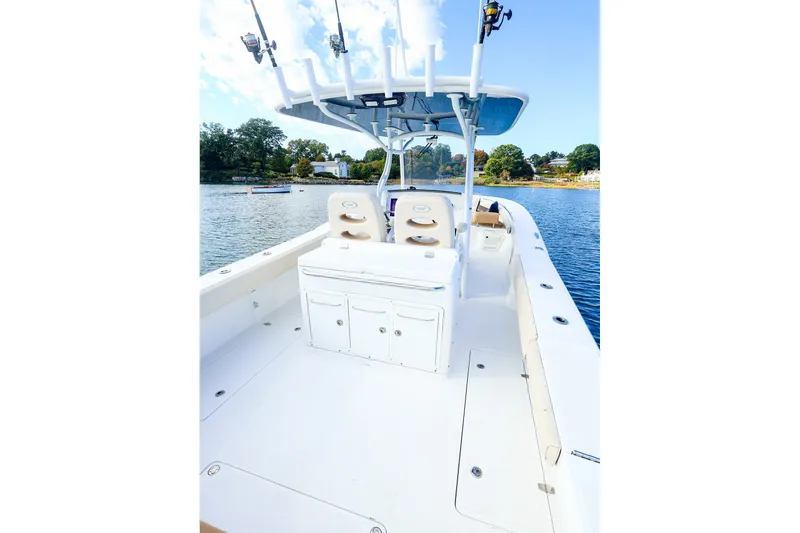 Slide: The Image of 2015 Southport 33 FE boat on calm water, featuring spacious deck and fishing rod holders. - 10