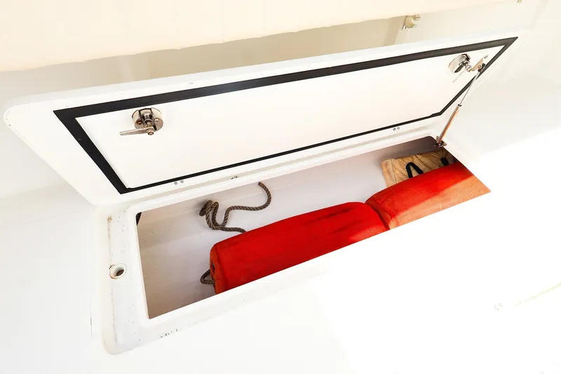 Slide: The Image of Storage compartment on a 2015 Southport 33 FE boat with red cushions and rope. - 33