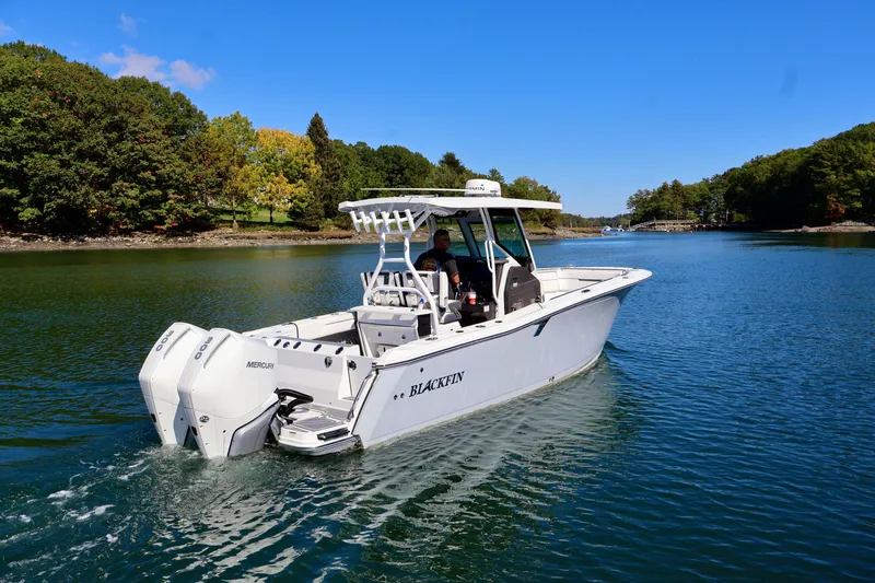 The Image of 2023 Blackfin 272 CC boat cruising on a serene lake with lush green surroundings. - 0