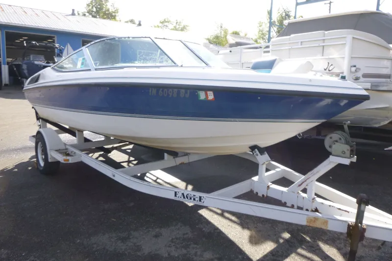 Slide: The Image of 1992 Chaparral boat on trailer, blue and white, parked outdoors. - 2