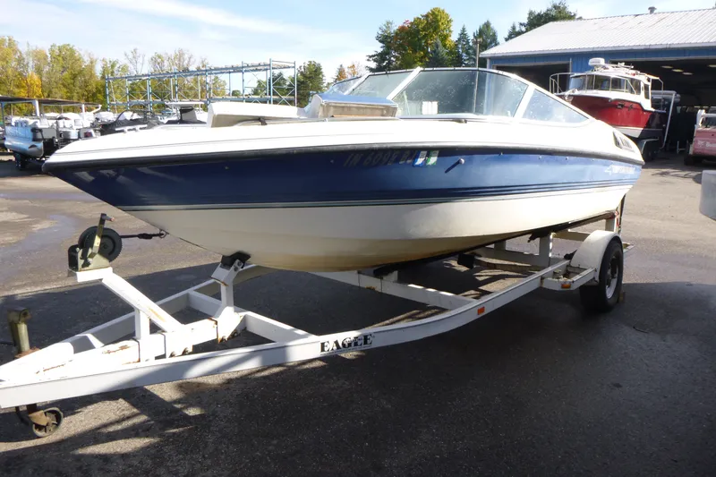 Slide: The Image of 1992 Chaparral boat on trailer, blue and white, parked outdoors near a storage facility. - 3