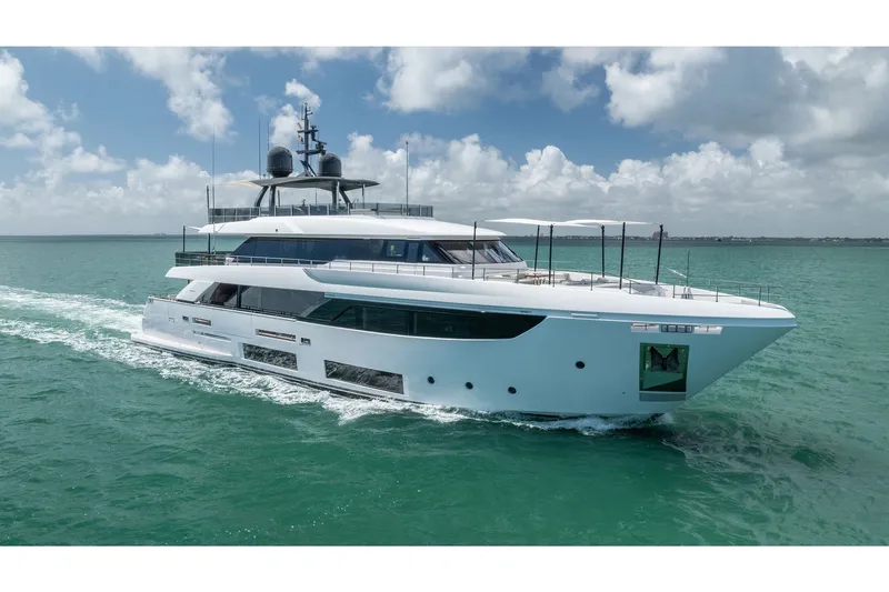 The Image of Luxurious 2023 Custom Line Navetta 33 yacht cruising on turquoise waters under a cloudy sky. - 1