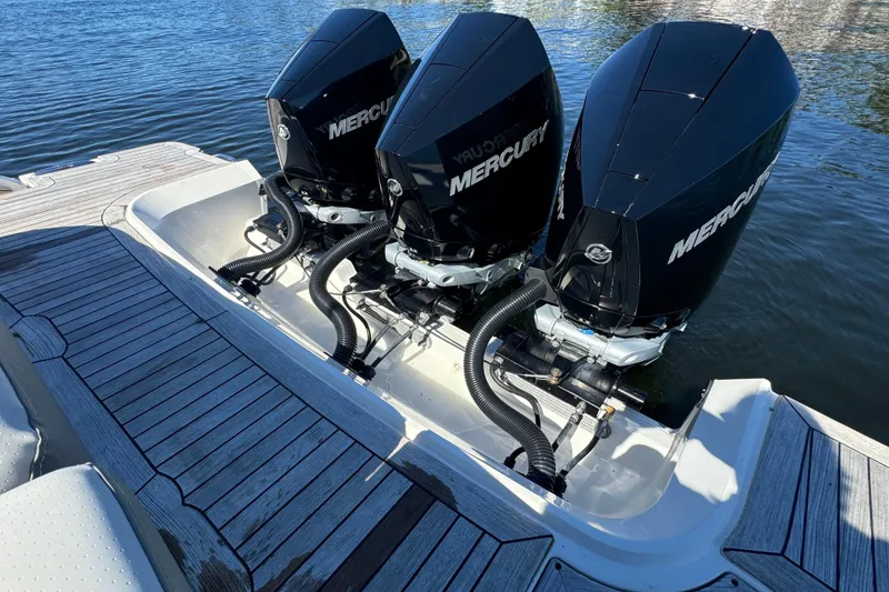 Slide: The Image of Three Mercury outboard engines are mounted on the stern of a Sea Ray SLX 400 boat, resting on calm water. - 24