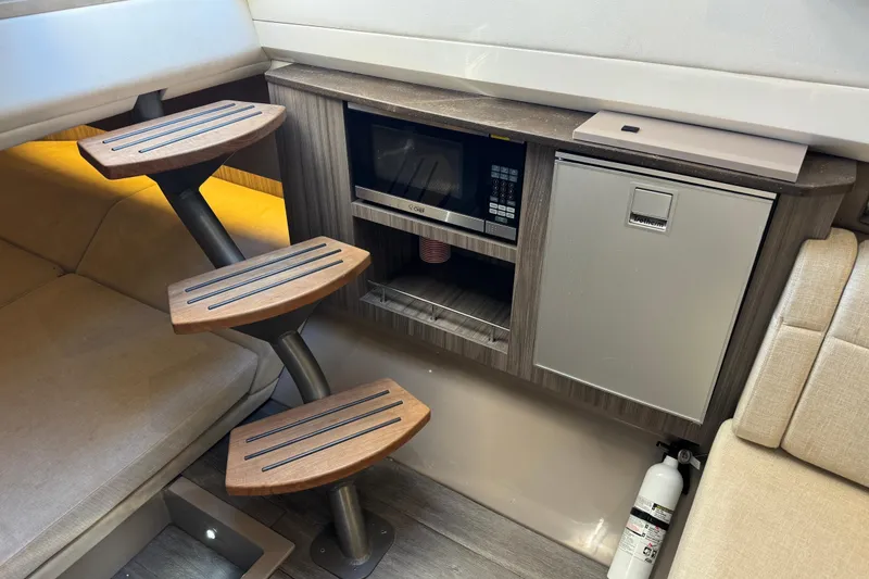Slide: The Image of Interior of the 2021 Sea Ray SLX 400 Outboard with wooden steps, microwave, and fridge. - 47