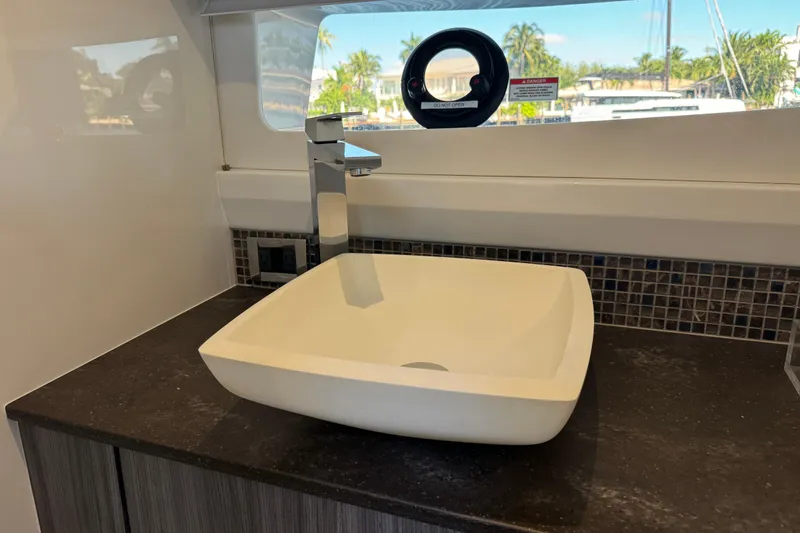 Slide: The Image of A modern square-shaped sink on a dark countertop, surrounded by a window view of boats. - 43