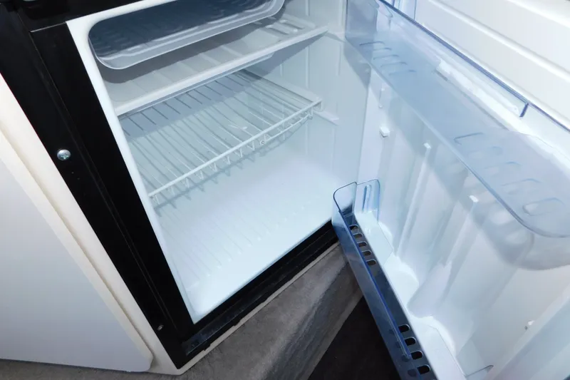 Slide: The Image of Open refrigerator inside a 1996 Sea Ray 250 Sundancer boat, showing empty shelves. - 62