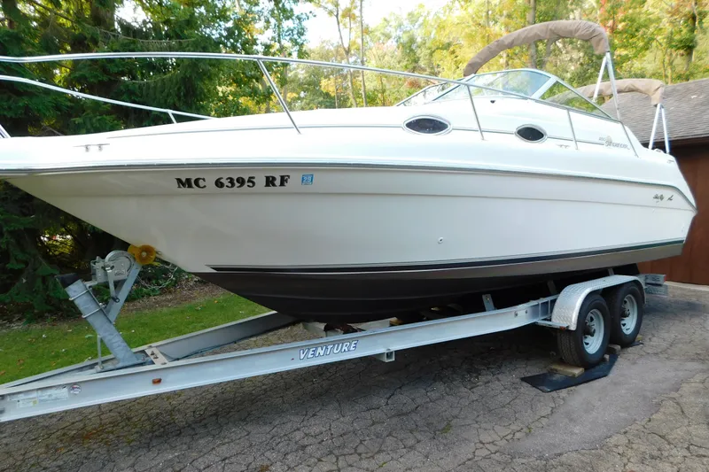 Slide: The Image of 1996 Sea Ray 250 Sundancer boat on trailer, parked outdoors, surrounded by trees. - 5