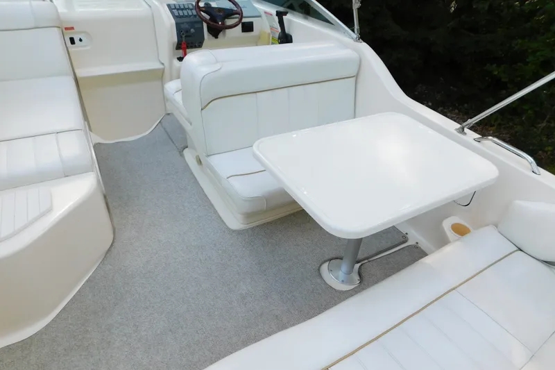 Slide: The Image of 1996 Sea Ray 250 Sundancer interior with white seating and table, showcasing helm and controls. - 27