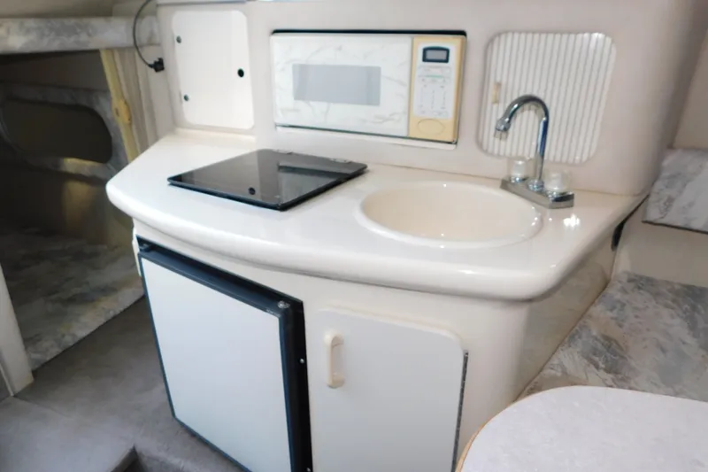 Slide: The Image of 1996 Sea Ray 250 Sundancer interior kitchenette with sink, stove, and microwave. - 54