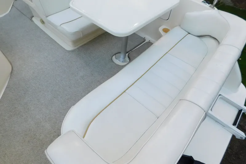 Slide: The Image of 1996 Sea Ray 250 Sundancer interior with white seating and table, showcasing luxury boat design. - 26