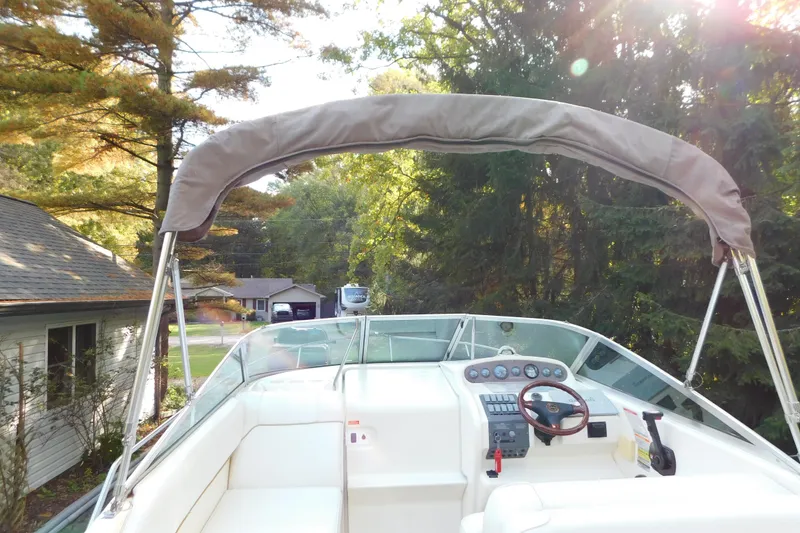 Slide: The Image of 1996 Sea Ray 250 Sundancer boat with canopy, steering wheel, and control panel in a wooded setting. - 29