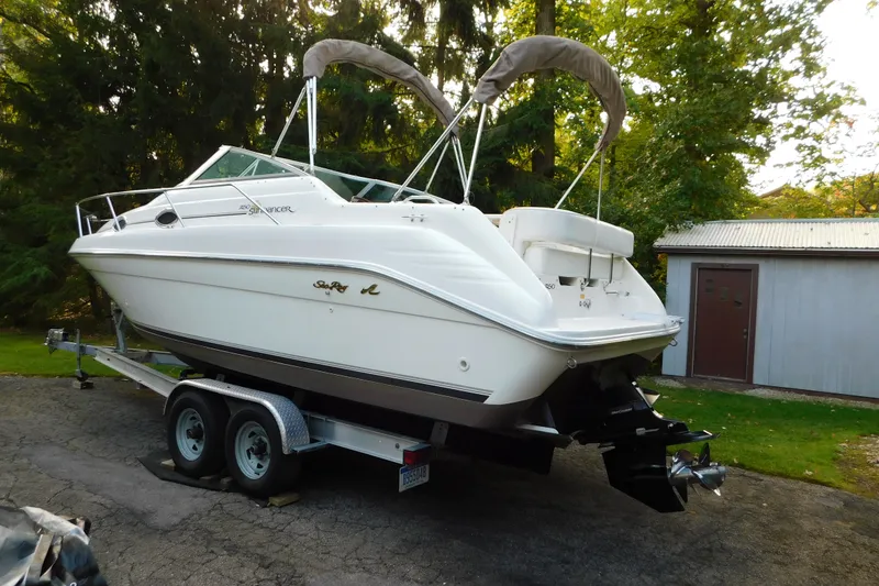 Slide: The Image of 1996 Sea Ray 250 Sundancer boat on trailer, parked outdoors near trees and a shed. - 7