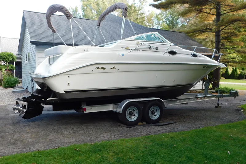 Slide: The Image of 1996 Sea Ray 250 Sundancer boat on trailer, parked near a house. - 2