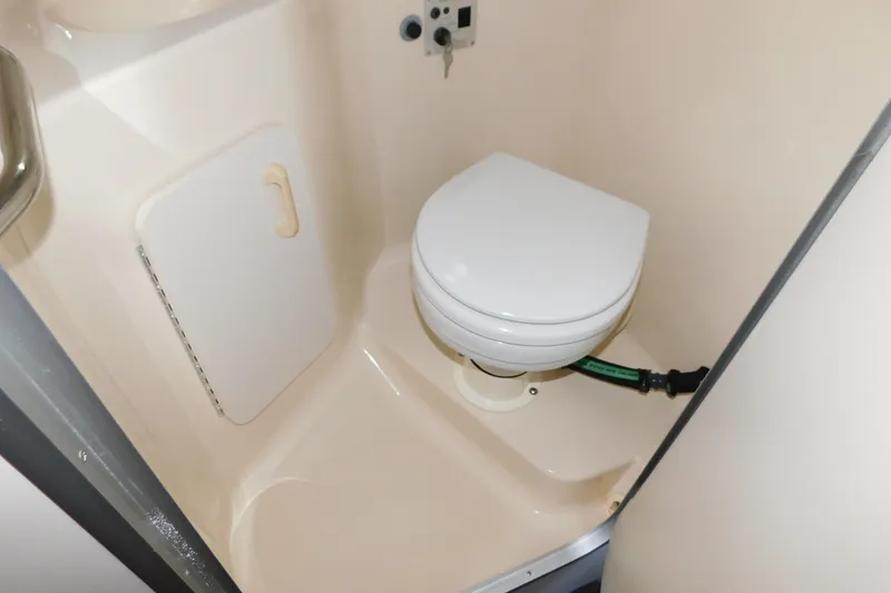Slide: The Image of 1996 Sea Ray 250 Sundancer boat bathroom with compact toilet and storage compartment. - 69