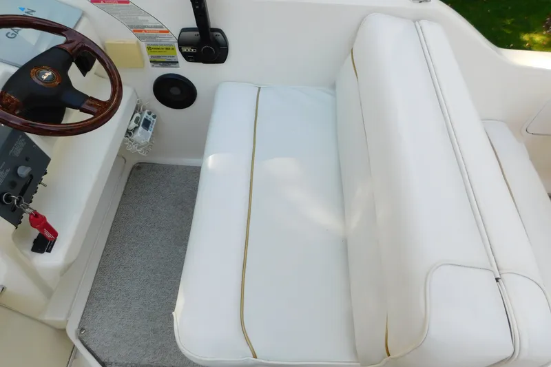 Slide: The Image of 1996 Sea Ray 250 Sundancer cockpit with white seating and wooden steering wheel. - 32