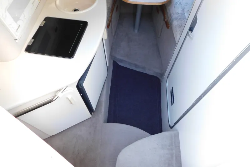 Slide: The Image of Interior of a 1996 Sea Ray 250 Sundancer boat, featuring a compact kitchenette and seating area. - 48