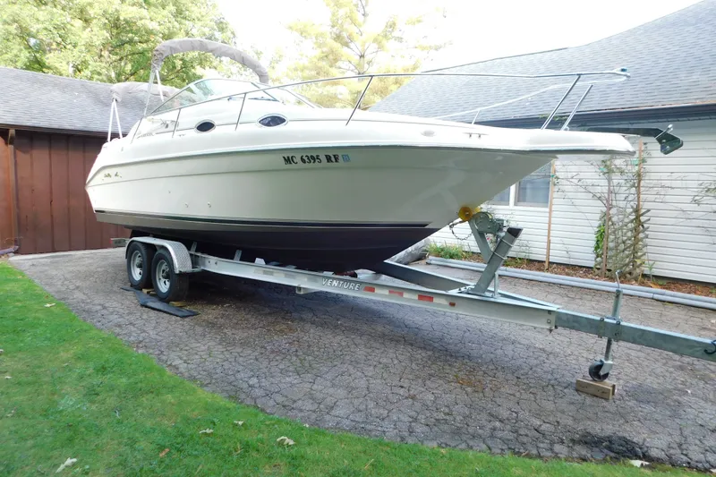 Slide: The Image of 1996 Sea Ray 250 Sundancer boat on trailer in driveway, surrounded by greenery. - 1