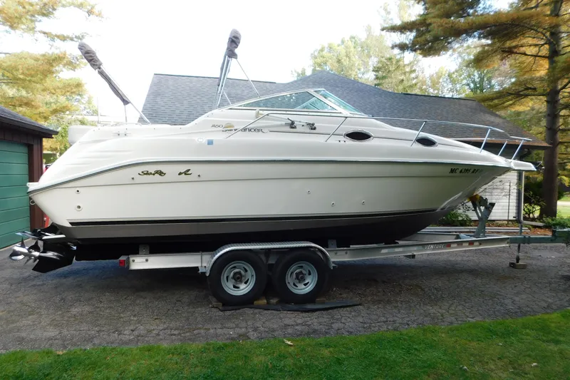 The Image of 1996 Sea Ray 250 Sundancer boat on trailer, parked outdoors near a house. - 0