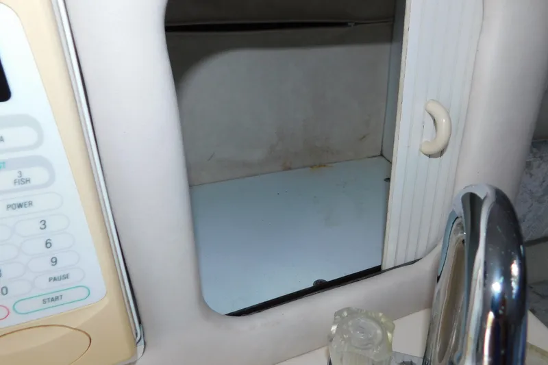Slide: The Image of Interior of a 1996 Sea Ray 250 Sundancer boat, featuring a microwave and storage area. - 60
