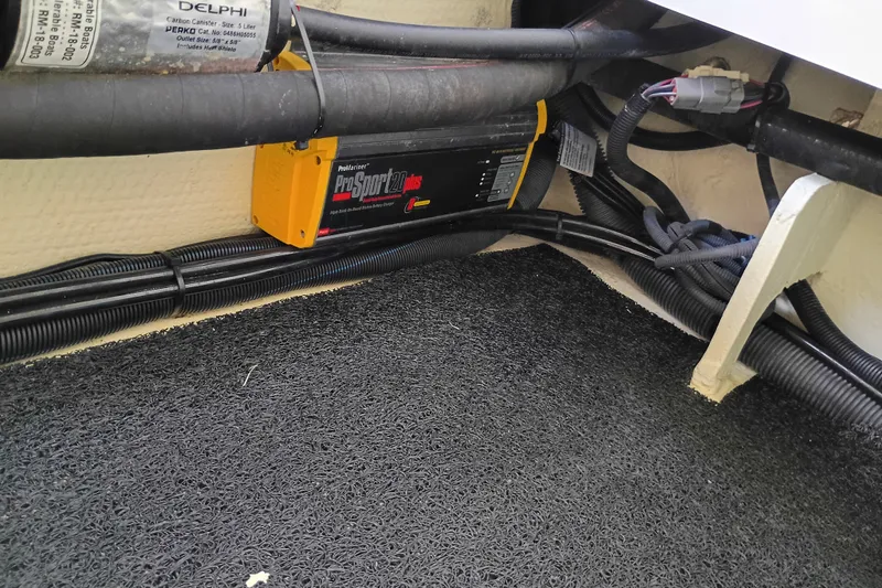 Slide: The Image of Battery charger and wiring inside a 2021 Regal 29 OBX boat compartment. - 32
