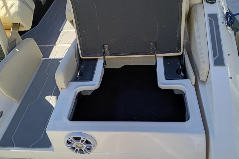 Slide: The Image of Open storage compartment on a 2021 Regal 29 OBX boat, featuring cushioned seating and speaker. - 38