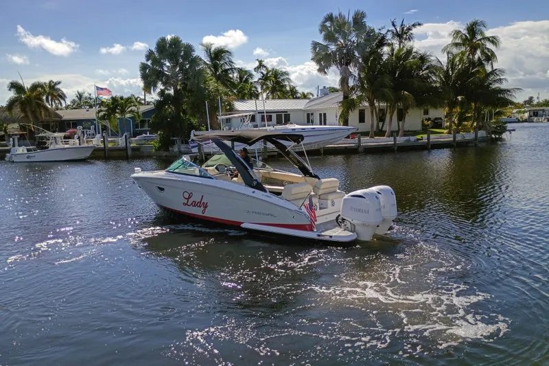 The Image of 2021 Regal 29 OBX boat cruising on a sunny, palm-lined waterway. - 4