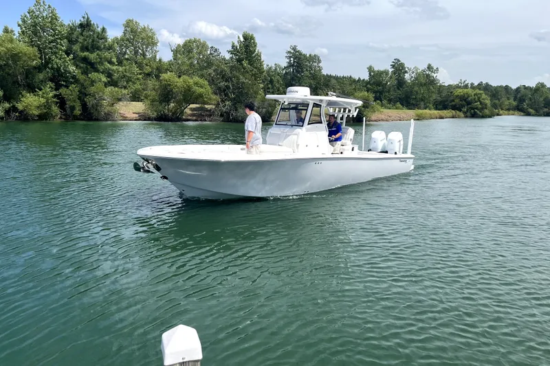 Slide: The Image of 2027 Tidewater 3100 Carolina Bay boat cruising on a serene river with lush greenery. - 5