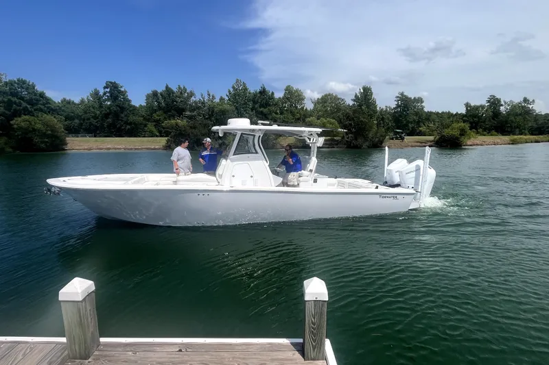 Slide: The Image of 2027 Tidewater 3100 Carolina Bay boat cruising on a serene lake with passengers onboard. - 4