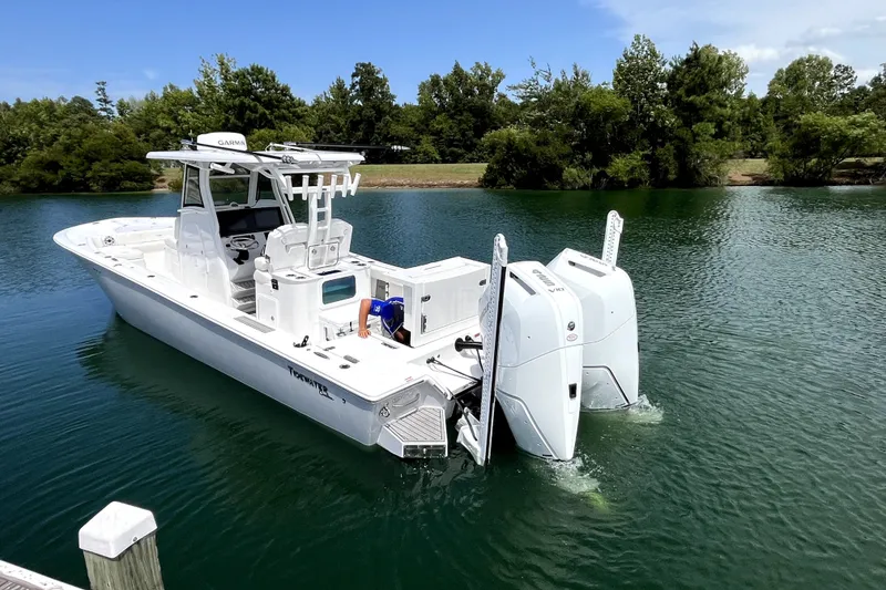Slide: The Image of 2027 Tidewater 3100 Carolina Bay boat on calm water, featuring dual outboard engines. - 3