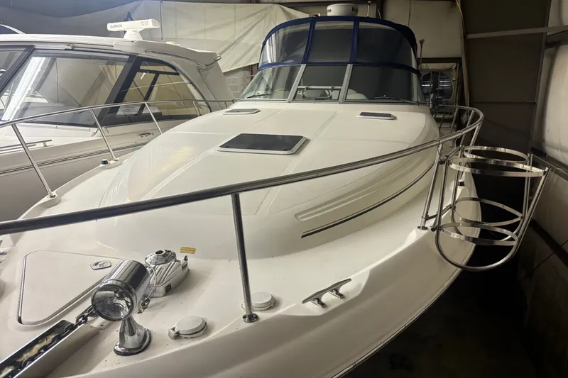 The Image of 2000 Sea Ray 340 Sundancer yacht in storage, showcasing sleek design and polished railings. - 0