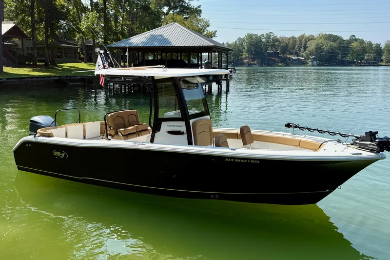 The Image of 2020 Sea Hunt Ultra 255SE boat on calm lake with dock and trees in background. - 0