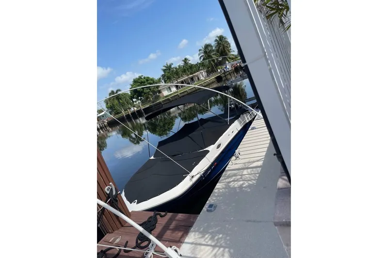 Slide: The Image of 2021 Bayliner VR6 Bowrider OB docked by a serene waterfront with palm trees. - 12