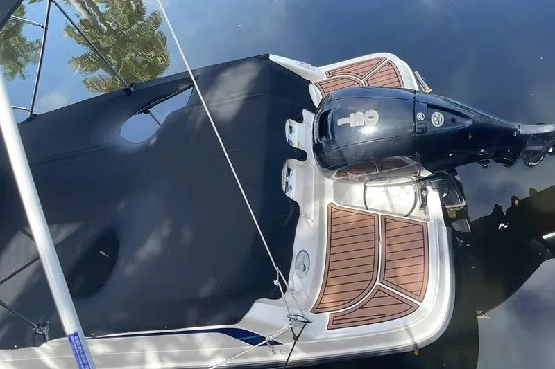 Slide: The Image of 2021 Bayliner VR6 Bowrider OB with outboard motor, covered and docked on calm water. - 2
