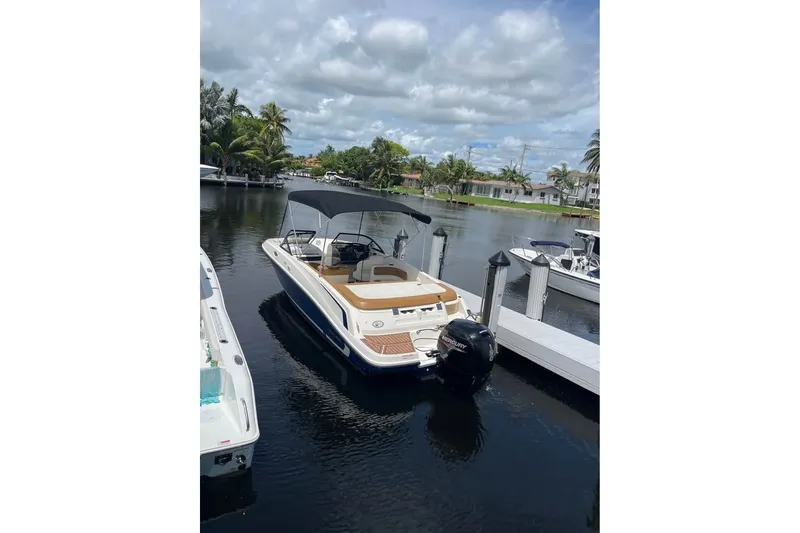 Slide: The Image of 2021 Bayliner VR6 Bowrider OB docked on a calm, scenic waterway. - 1
