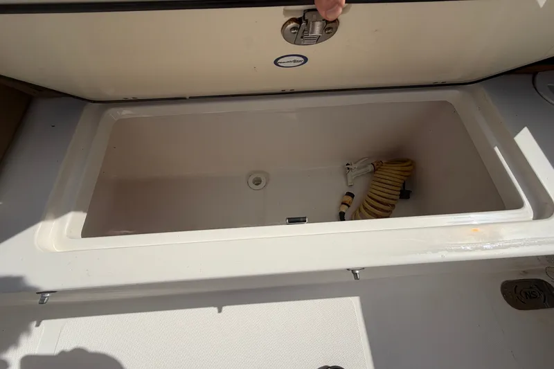 Slide: The Image of Open storage compartment on 2023 NauticStar 2602 Legacy boat with coiled hose inside. - 16
