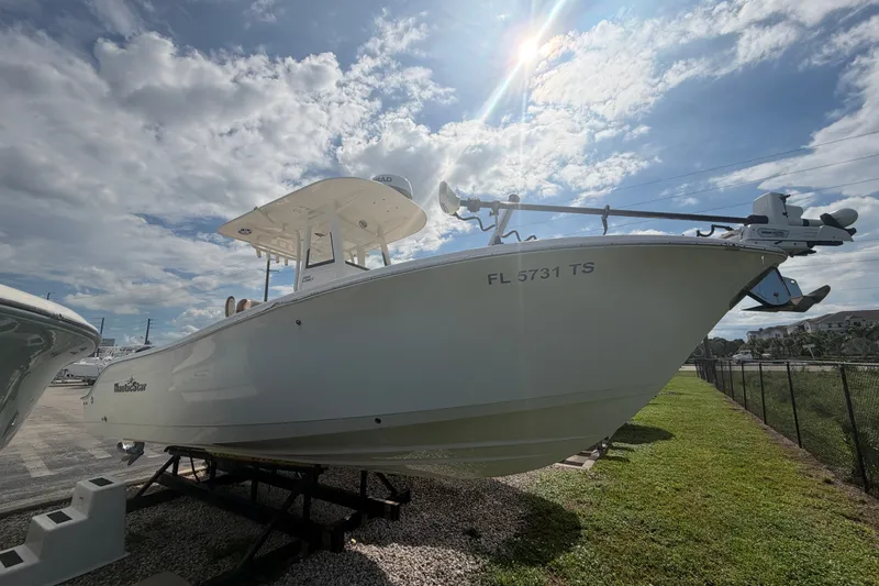 The Image of 2023 NauticStar 2602 Legacy boat displayed outdoors under a partly cloudy sky. - 0