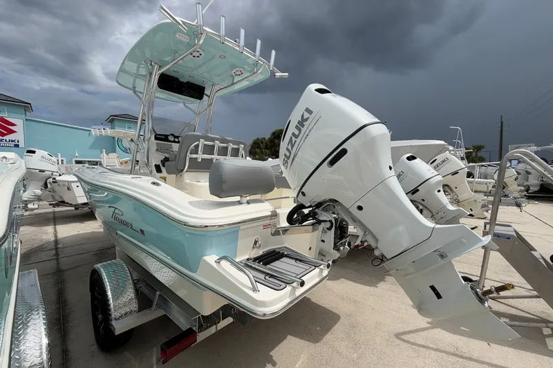 Slide: The Image of 2027 Pioneer 202 Sportfish boat with Suzuki outboard motor, parked on a trailer under cloudy skies. - 4