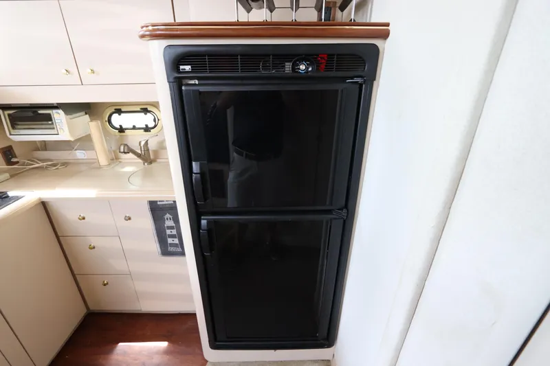 Slide: The Image of 1999 Cruisers Yachts 3750 Motoryacht kitchen with black refrigerator and beige cabinetry. - 35