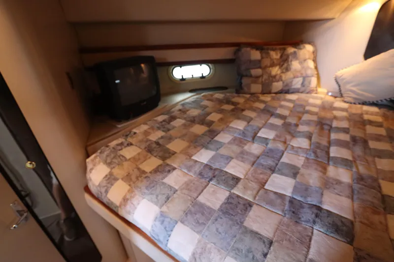 Slide: The Image of 1999 Cruisers Yachts 3750 Motoryacht bedroom with checkered bedding and a small TV. - 39