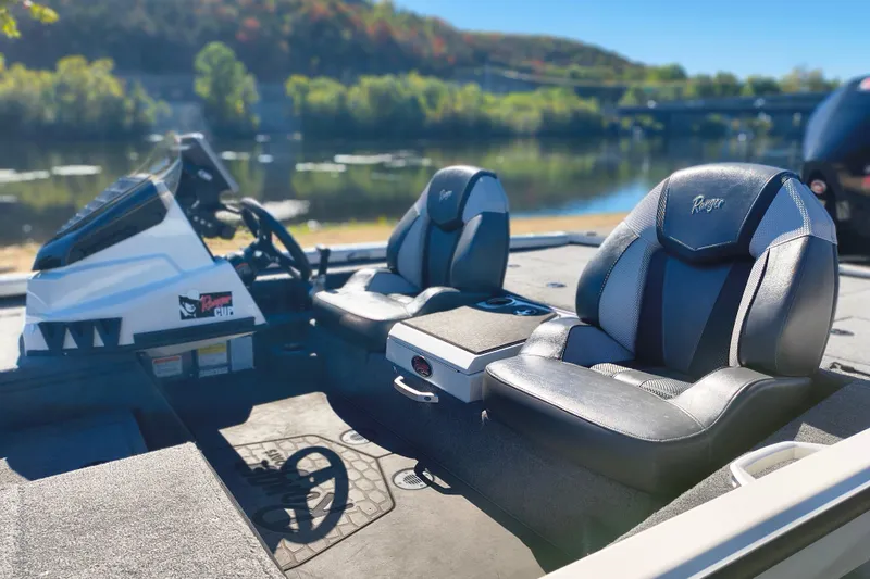 Slide: The Image of 2025 Ranger ALPHA 208 boat interior with sleek black seats by a scenic lake. - 19