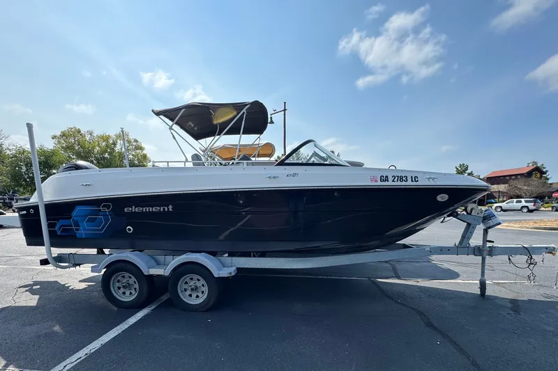 Slide: The Image of 2020 Bayliner Element E21 boat on trailer in parking lot under clear sky. - 0