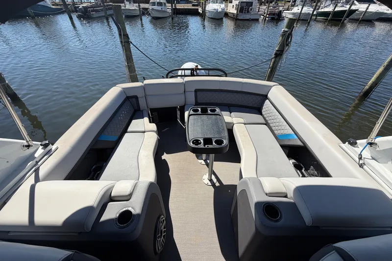 Slide: The Image of 2023 Godfrey AquaPatio 255 ULC pontoon boat interior with plush seating and table, docked at marina. - 15